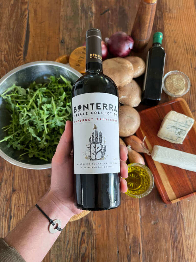 Bottle shot of Bonterra Estate Collection Cabernet Sauvignon 2021, on top of ingredients view