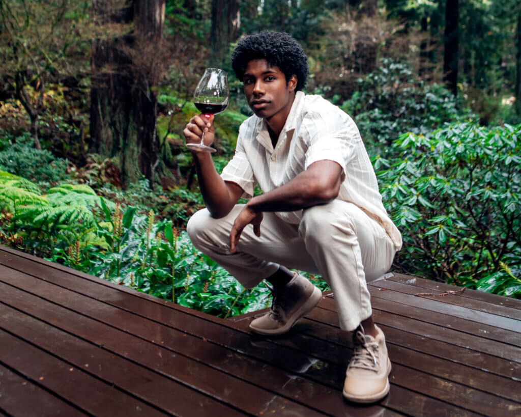 Man holding a glass of bonterra wine and wearing a pair of allbirds shoes