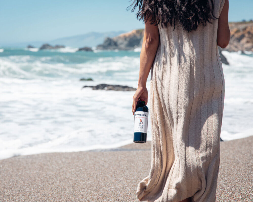 woman holding a bottle of wine at the beach