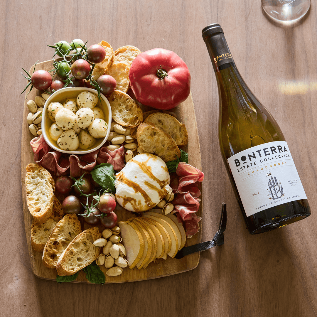 Savory prosciutto, oil-drizzled Mozzarella and tomatoes-on-the-vine are accented by fresh basil and warm baguette slices in this Caprese-inspired board paired with Bonterra Estate Chardonnay.