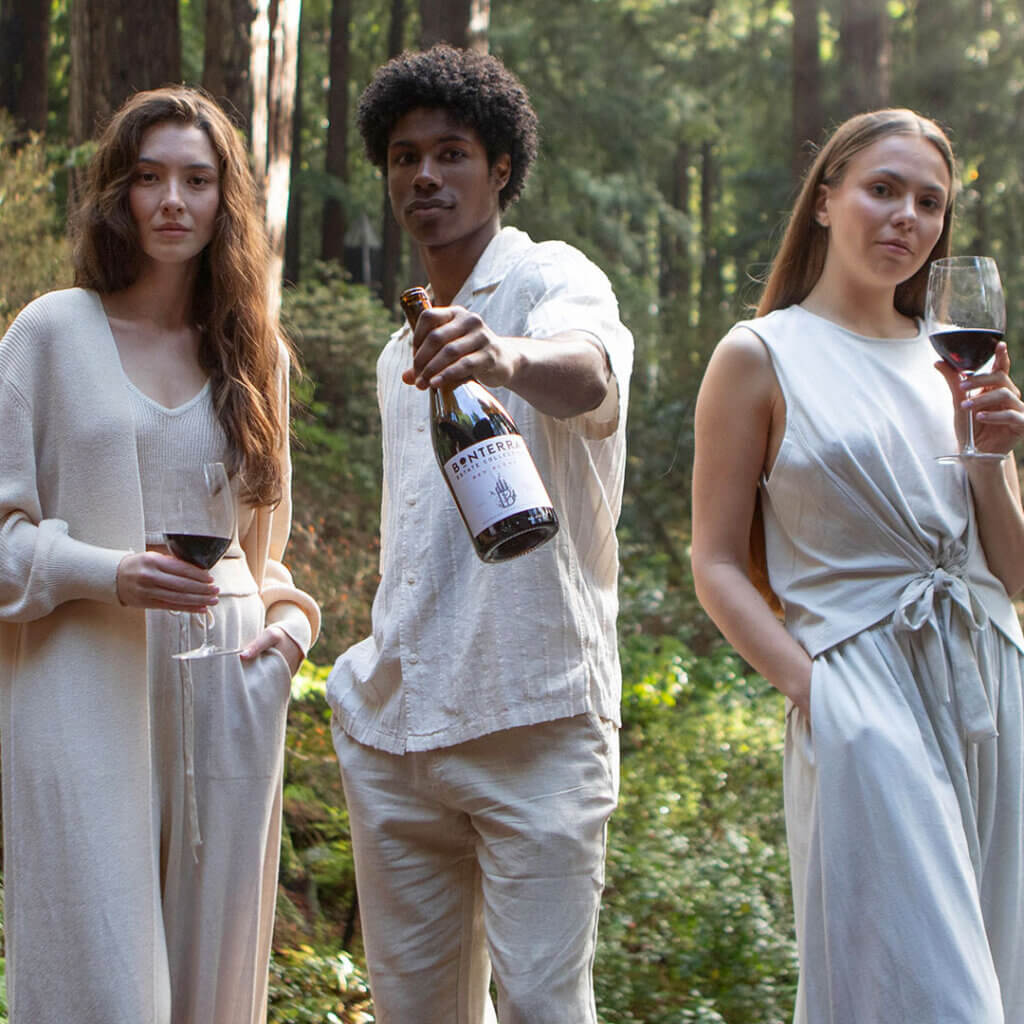 three people sharing a bottle of wine outdoors